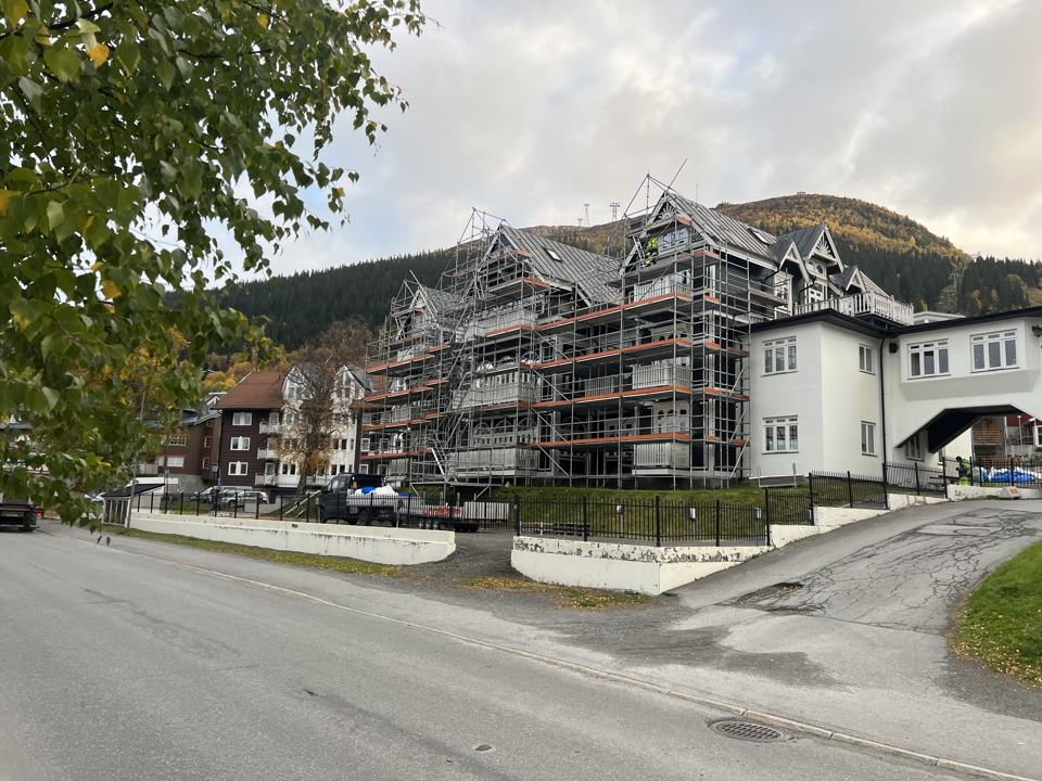 Flerbostadshus med ställning och fjället i bakgrunden