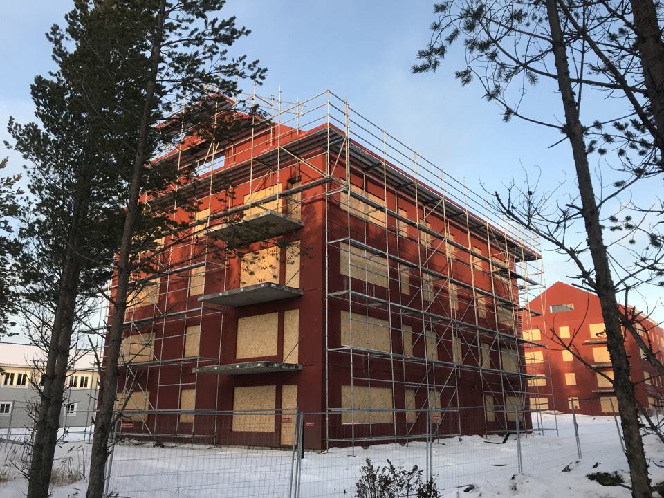 Rött flerbostadshus med ställning i snö