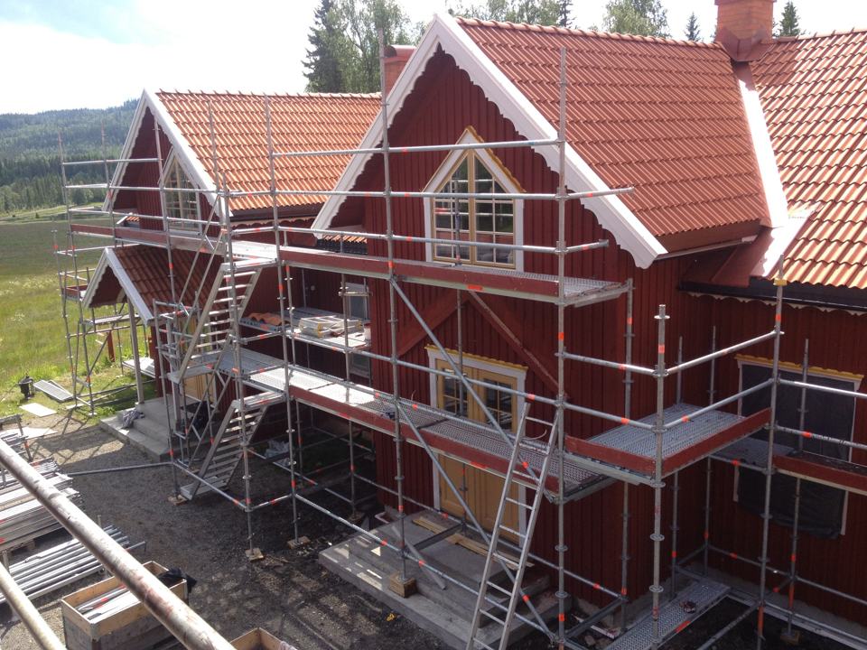 Röd villa med ställning längs taket inför takbyte