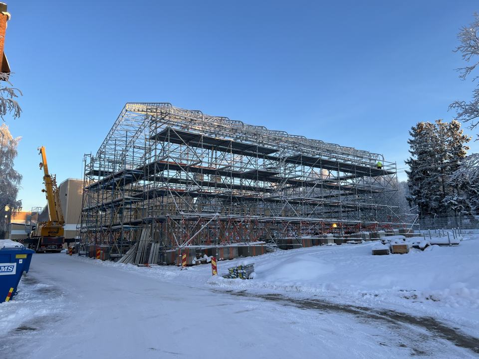 Stor ställning runt ett bygge i snö och vinterljus